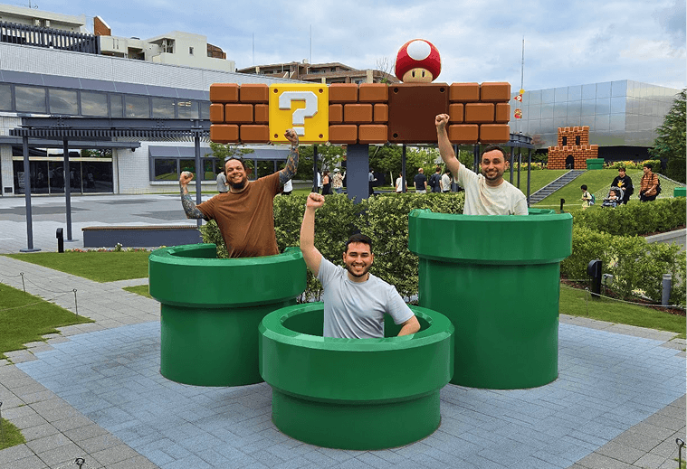 Participantes posando dentro dos canos verdes do Super Mario durante a viagem ao Japão